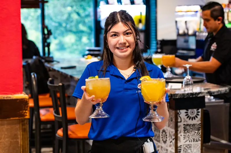 Servers with mango margaritas at the bar